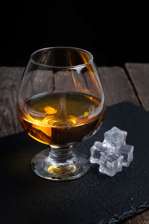 glass with whiskey with ice on wooden tableの写真素材