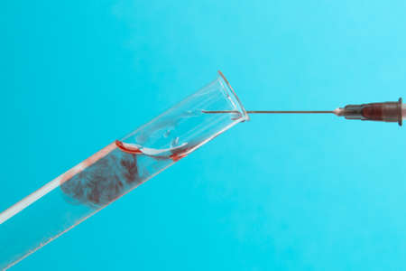 medical syringe needle with a drop of blood and a glass test tubeの写真素材