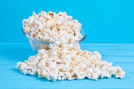 popcorn in a glass bowl on a blue tableの写真素材