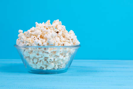popcorn in a glass bowl on a blue table. popcorn with copy spaceの写真素材