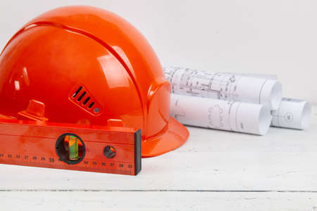 Safety helmet, paper drawings, blueprits and building level. Architect engineer work.