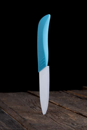 Kitchen knife is stuck in a wooden board. Close-up knife for food on a black backgroundの写真素材