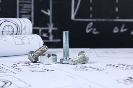 Wrench, bolts and nuts on background of engineering drawings. Science, mechanics and mechanical...