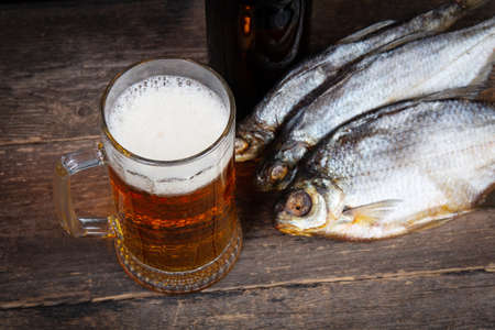 Glass of beer and dry fish on a wooden tableの写真素材
