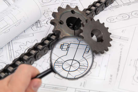 View of engineering drawings and sprocket for driving industrial roller chain through a magnifying glassの写真素材