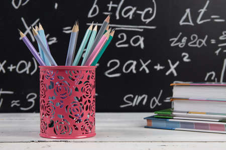 Pencils and books on blackboard background with mathematical formulas. Education concept.の写真素材