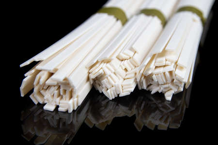 Uncooked chinese and japanese udon noodles on black table