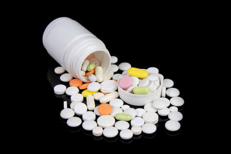 colored medical drugs and pills on black tableの写真素材