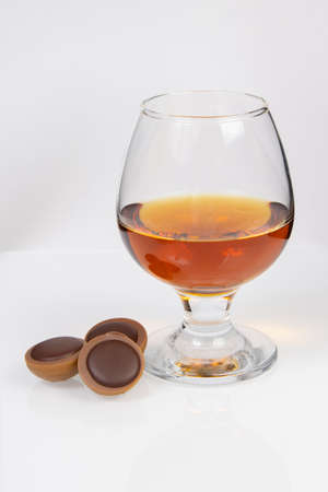 glass with cognac and chocolate on a white backgroundの写真素材