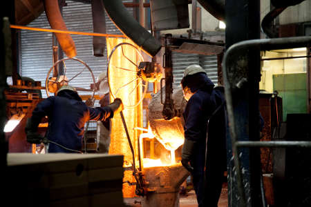 Steel workers, pourning moulten metal from crucible