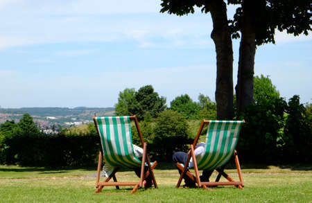 Two people relaxing in deckchairs in gardenの写真素材