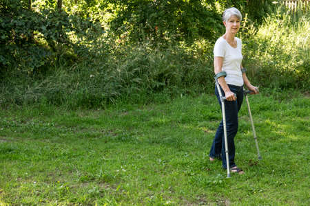 Senior woman walking with crutches after hip replacementの写真素材
