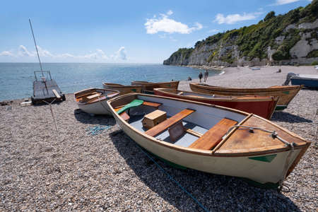 Wooden boats washed up on shingle beach at Beer, South Devon, UK.