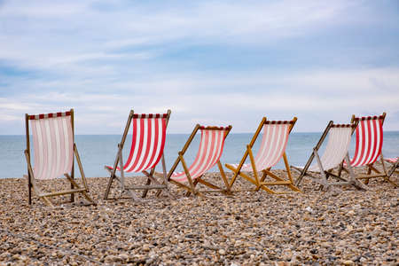Deckchairs on beach, typical english seaside holiday scene, red and white stripesの写真素材