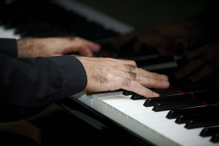 Man's hands playing the grand piano low keyの写真素材