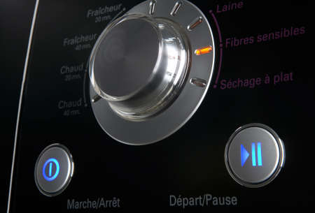 Close up of a modern washing machine control pannel, with timer and options low key against black...