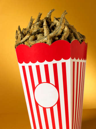 Ironic image of Cardboard Box with fried fish instead pop corn copy space