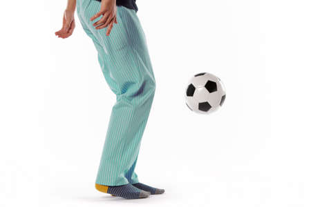 Young man dressed in pyjama and football ball isolated on white