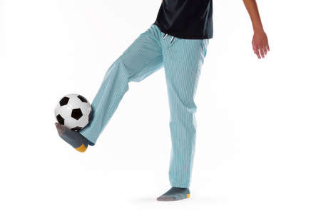 Young man dressed in pyjama and football ball isolated on whiteの写真素材