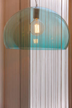 Retro lamp in blue tone with curtain and window. Verticalの写真素材
