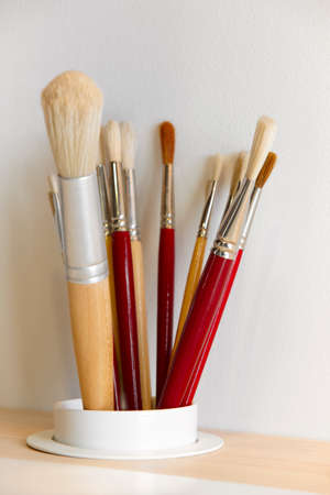 Different kinds of paintbrushes over a wooden table. Verticalの写真素材