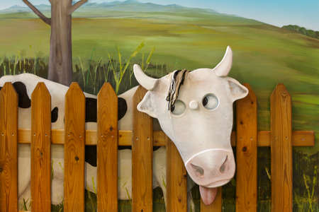 Cow figure with wooden fence and green background. Horizontalの写真素材