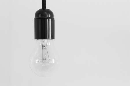 Switched off bulb and black cap over a white wall. Horizontalの写真素材