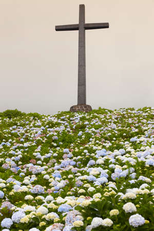 Catholic cross and hydrangeas garden on a cloudy day. Verticalの写真素材