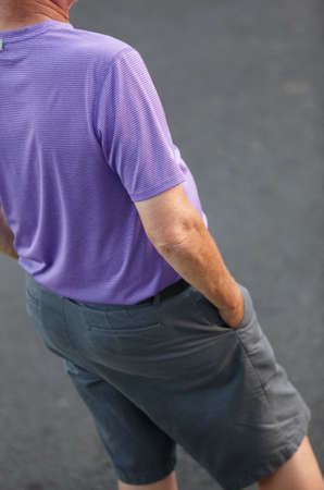 Senior man dressed in shirt and shorts on a street. Backの写真素材