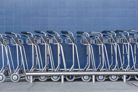 Airport trolley parking lot with empty trolleys and blue wall. Horizontalの写真素材