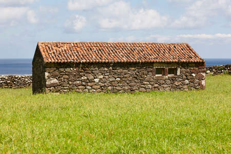 Antique stone house in the countryside with ocean background. Azores, Portugalのeditorial素材