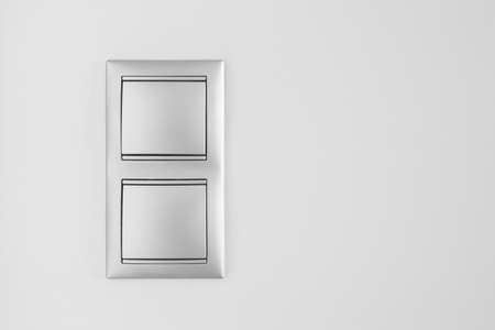 Double metallic light switch over a white wall. Copy space. Horizontal