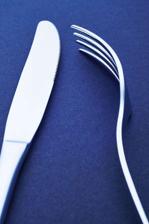 Knife and fork detail over a blue background. Cutlery. Verticalの写真素材