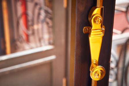Golden metallic window lock detail with out of focus background. Horizontalの写真素材