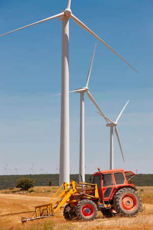 Wind turbine and tractor countryside. Clean alternative renewable energy. Vertical