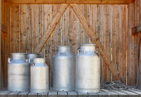 Metallic milk containers on a wooden background. Farming. Horizontal