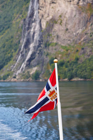 Norwegian flag. Norway fjord landscape with waterfall and water. Verticalの写真素材