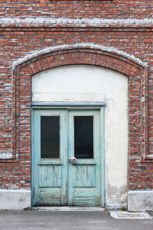 Antique brick facade with green doors. Old style warehouse entrance. Construction