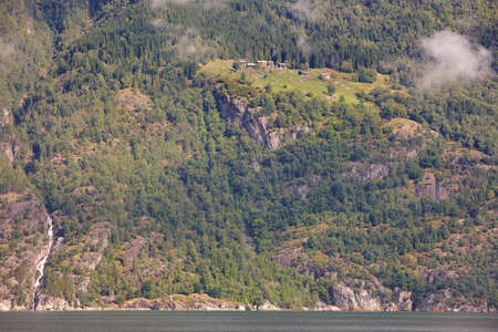 Norwegian fjord landscape with waterfall and houses. Sorfjorden. Norway. Horizontal