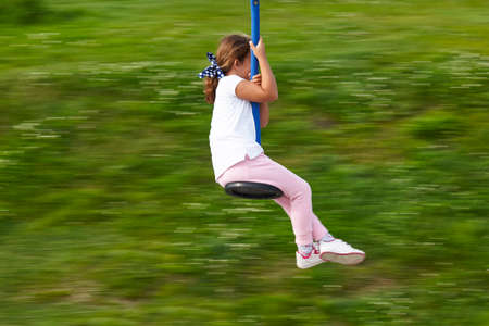 Girl on a zip line with green background. Entertainment. Recreationalの写真素材
