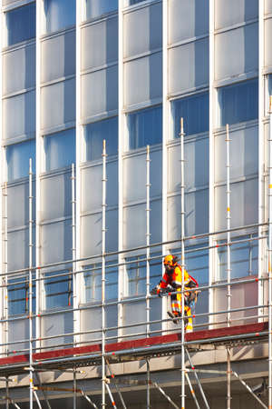 Construction worker mounting a scaffolding structure on a building facadeのeditorial素材