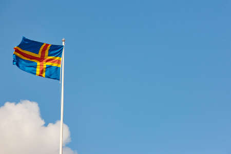 Aland islands flag over a blue sky. Finland background. Horizontal