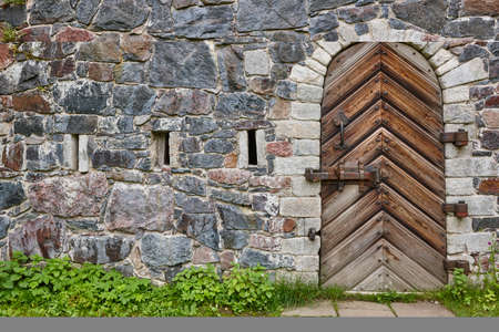 Stone wall with antique castle locked wooden door. Vintage background の写真素材