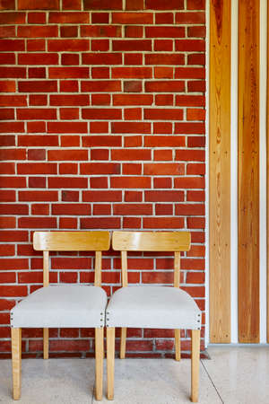 Building interior with wooden chairs and red brick wall. Verticalの写真素材