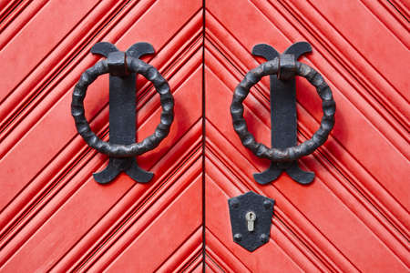 Antique metallic door knob on a red wooden doors. Horizontalの写真素材