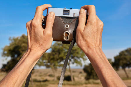 Woman hands holding a film vintage camera taking pictures