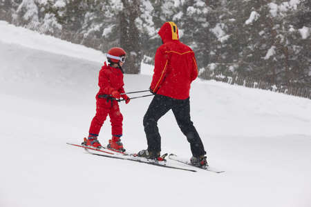 Child learning how to ski with an instructor. Winter sportの写真素材