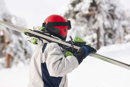 Skier carrying skis on a snowy forest landscape. Winter sportの写真素材