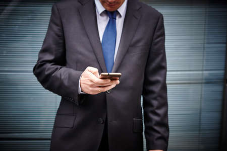 Business man texting with mobile phone. Working time. Outdoors. Messageの写真素材