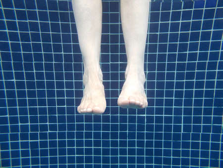 Feet on a swimming pool. Summertime. Relaxing time. Horizontal